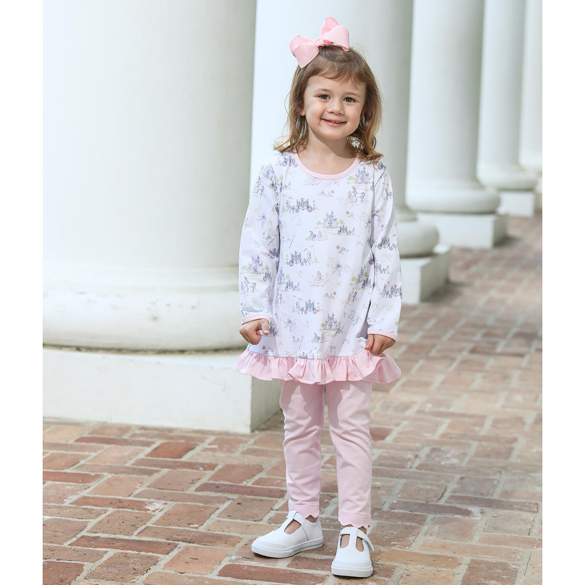 Little girl in a fairy princess print tunic top with ruffle and pink pants.