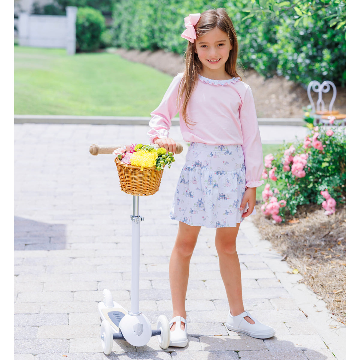 Young girl wearing a pink long sleeve shirt with a fairytale print skort