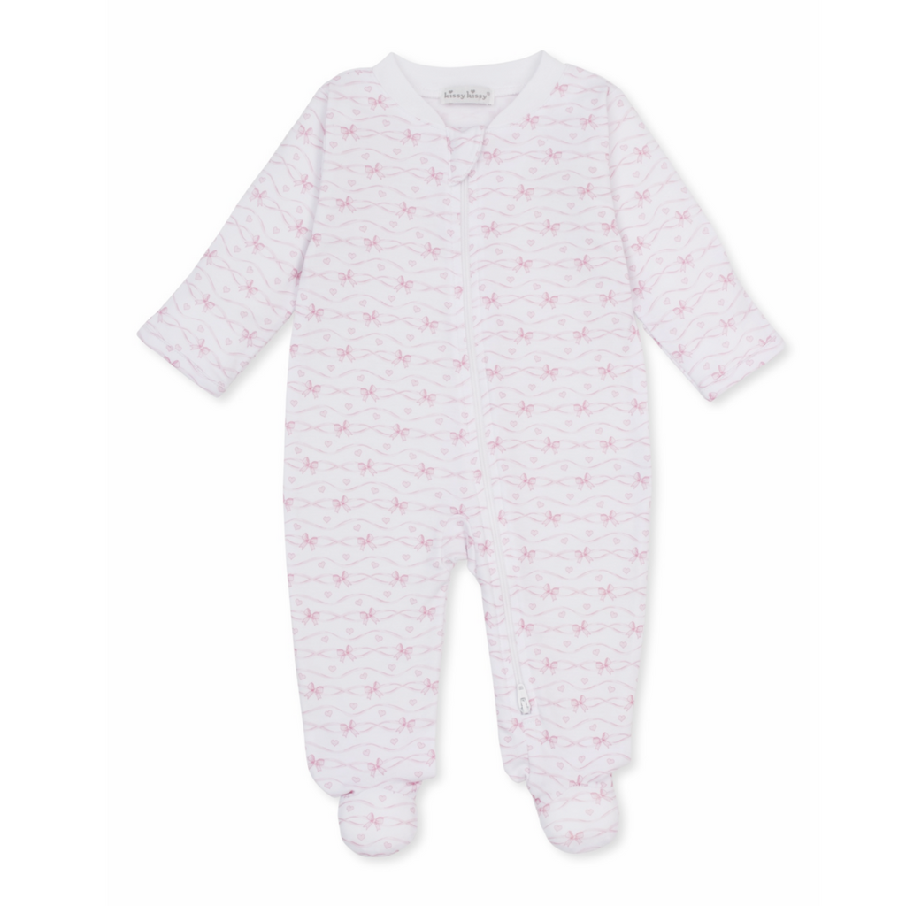 A white long-sleeve baby girl zip-up footed sleeper with a delicate light pink bow and heart pattern and Kissy Kissy brand label.