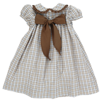 A toddler girl's dress with a beige, tan, blue and brown plaid pattern, featuring a large brown bow at the back.