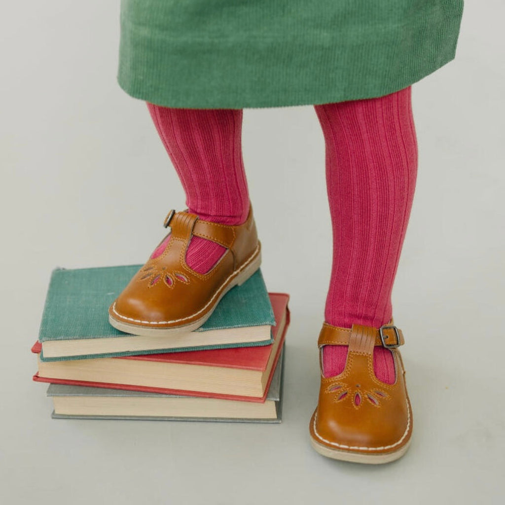 Little girl wearing brown shoes and pink socks standing on a stack of books