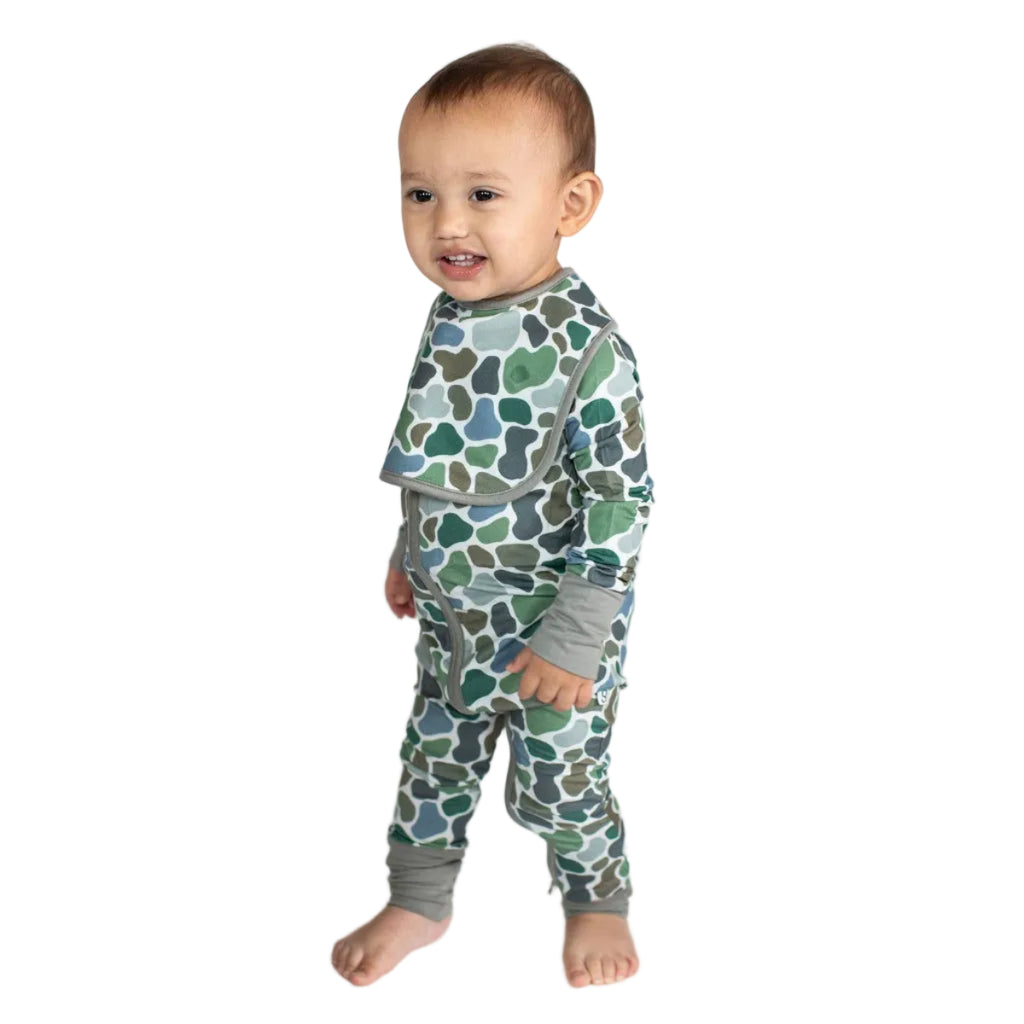 Baby wearing a green and gray patterned outfit on a white background