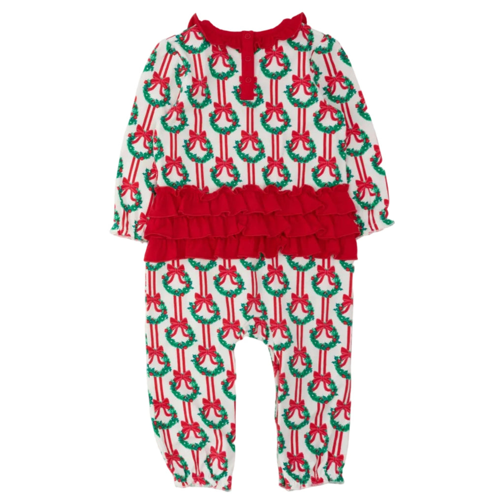 A toddler's holiday-themed long-sleeve romper with an all-over Christmas wreath and bow print on a white base, featuring a prominent red ruffle waistband and red tie detail at the neckline.