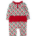 A toddler's holiday-themed long-sleeve romper with an all-over Christmas wreath and bow print on a white base, featuring a prominent red ruffle waistband and red tie detail at the neckline.
