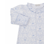 Closeup of a baby girl gown with ruffled collar and blue bows and floral pattern.