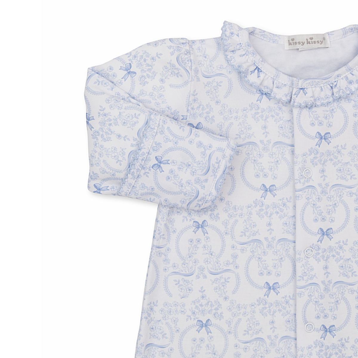 Closeup of a baby girl gown with ruffled collar and blue bows and floral pattern.