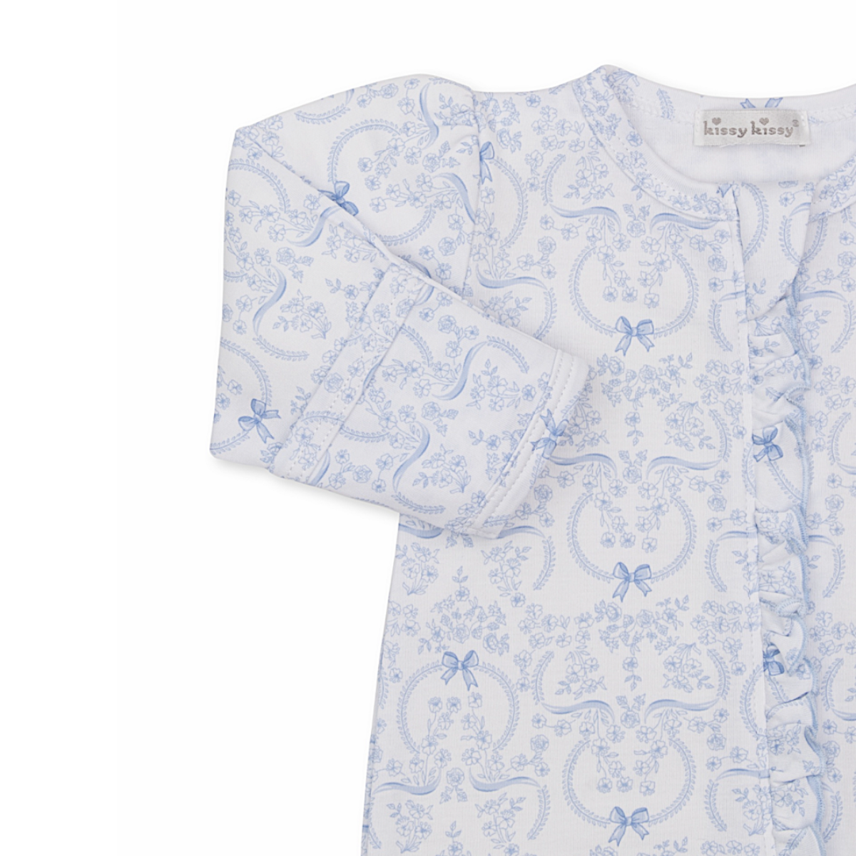 Closeup of a baby girl footie with ruffle trim zip front and blue coquette bows and floral pattern.