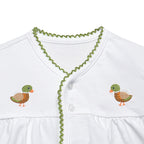 Close up view of a white baby two-piece diaper set consisting of a short-sleeve button-front top with green trim and embroidered duck motifs.
