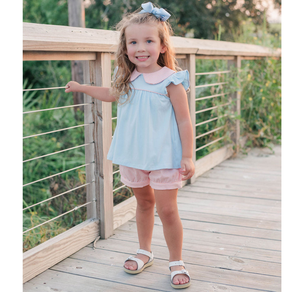 Toddler girl wearing a blue knit top with coral stripe shorts set