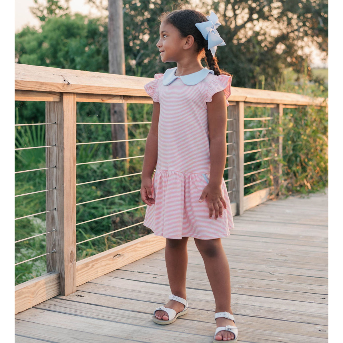 Toddler girl wearing a coral striped knit dress with blue collar