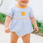 A baby boy wearing a bubble with light blue and white stripes, featuring orange trim on the crew neck and sleeve cuffs, and an appliqued pumpkin design on the chest.