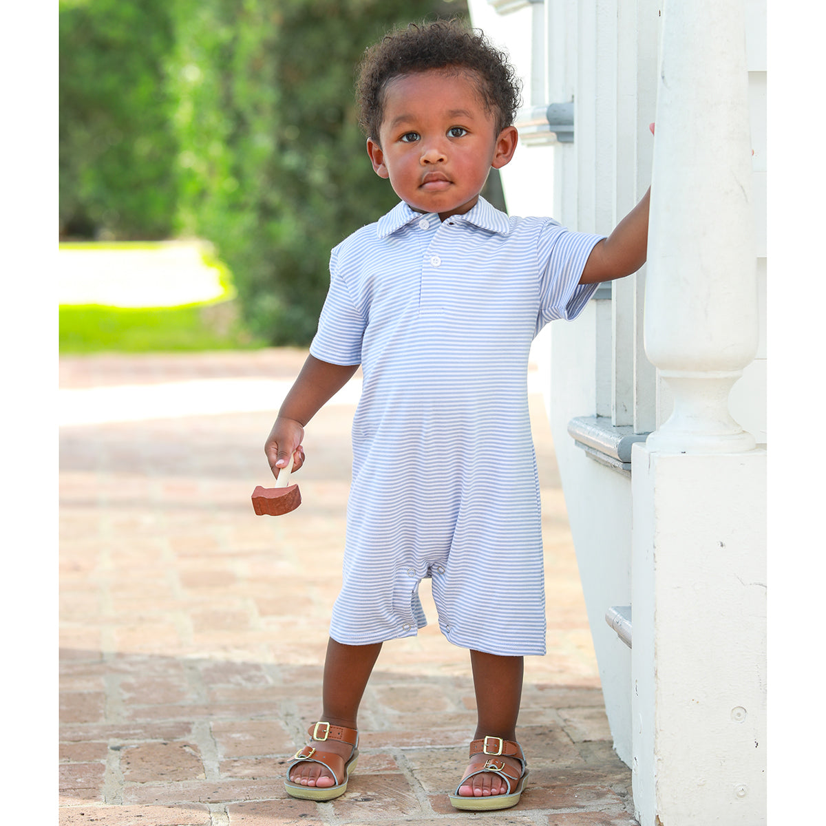 Baby boy wearing a light blue striped knit polo romper with collar
