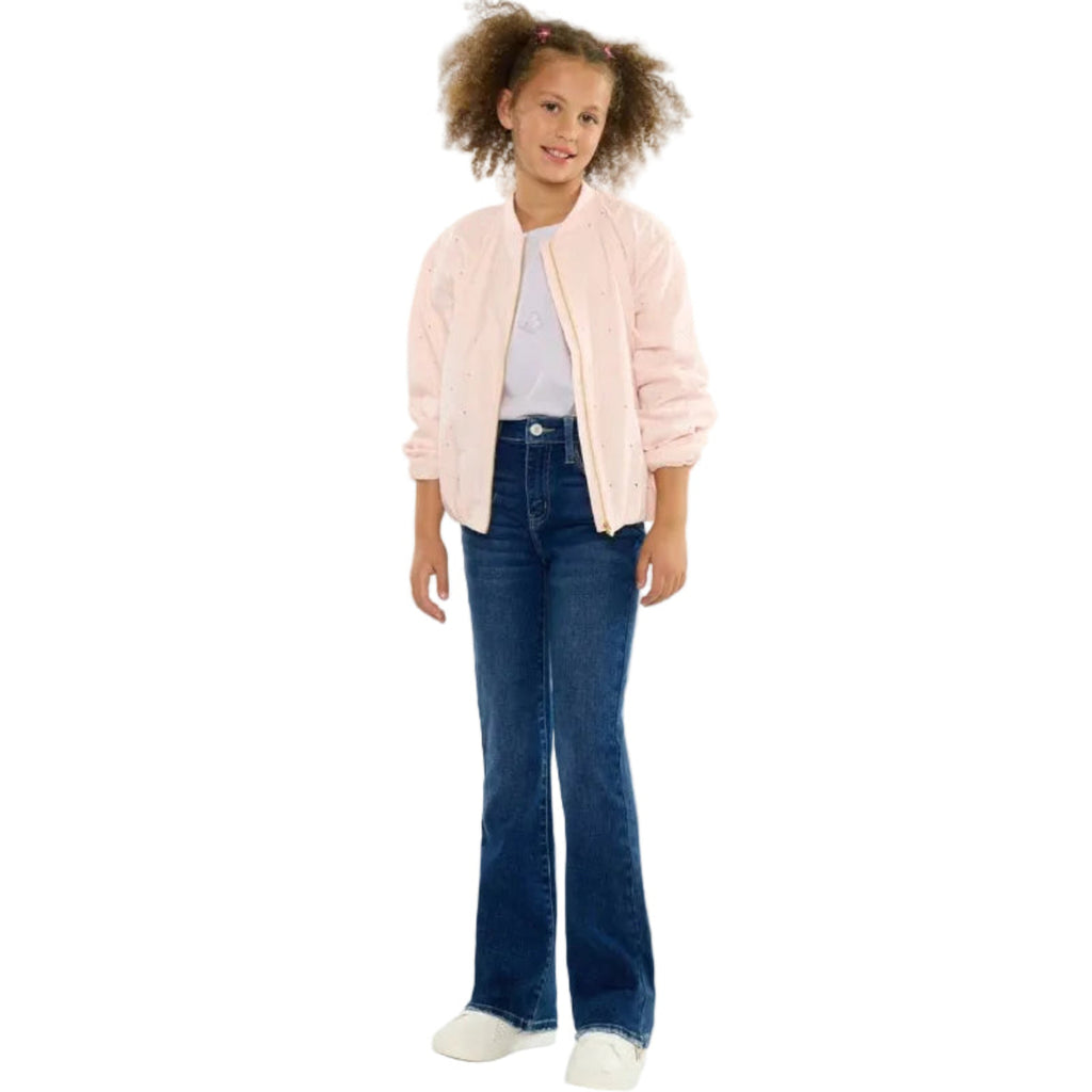 Young girl wearing a pink jacket, white shirt, blue jeans, and white sneakers on a white background