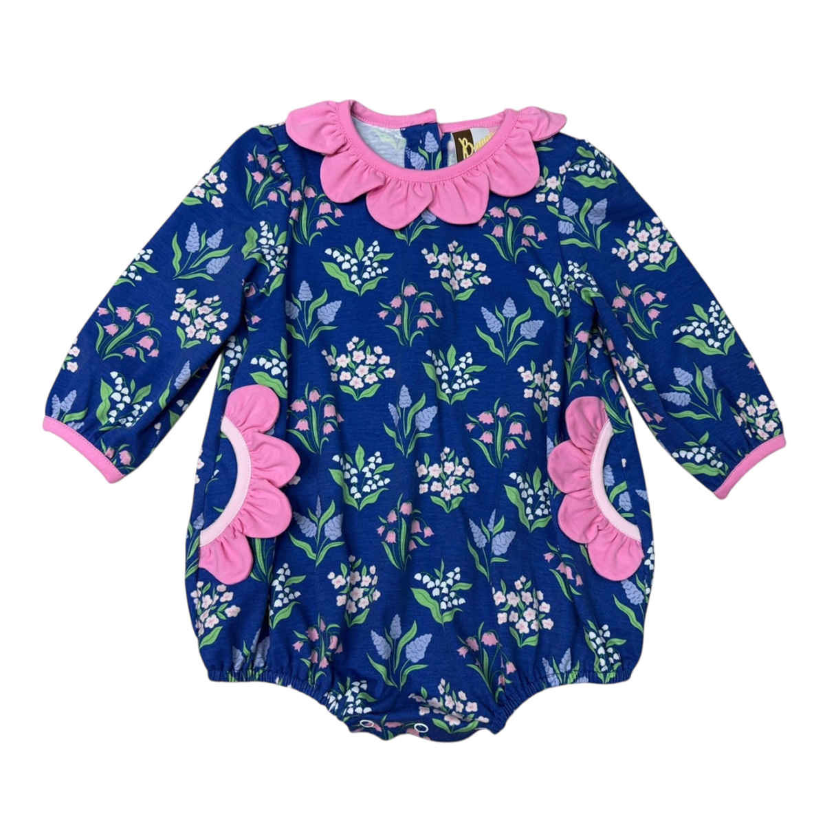 A girl's long-sleeve bubble with a navy blue background and a vivid floral print, featuring a prominent pink petal trim on the pockets and neckline and pink trim on the cuffs.