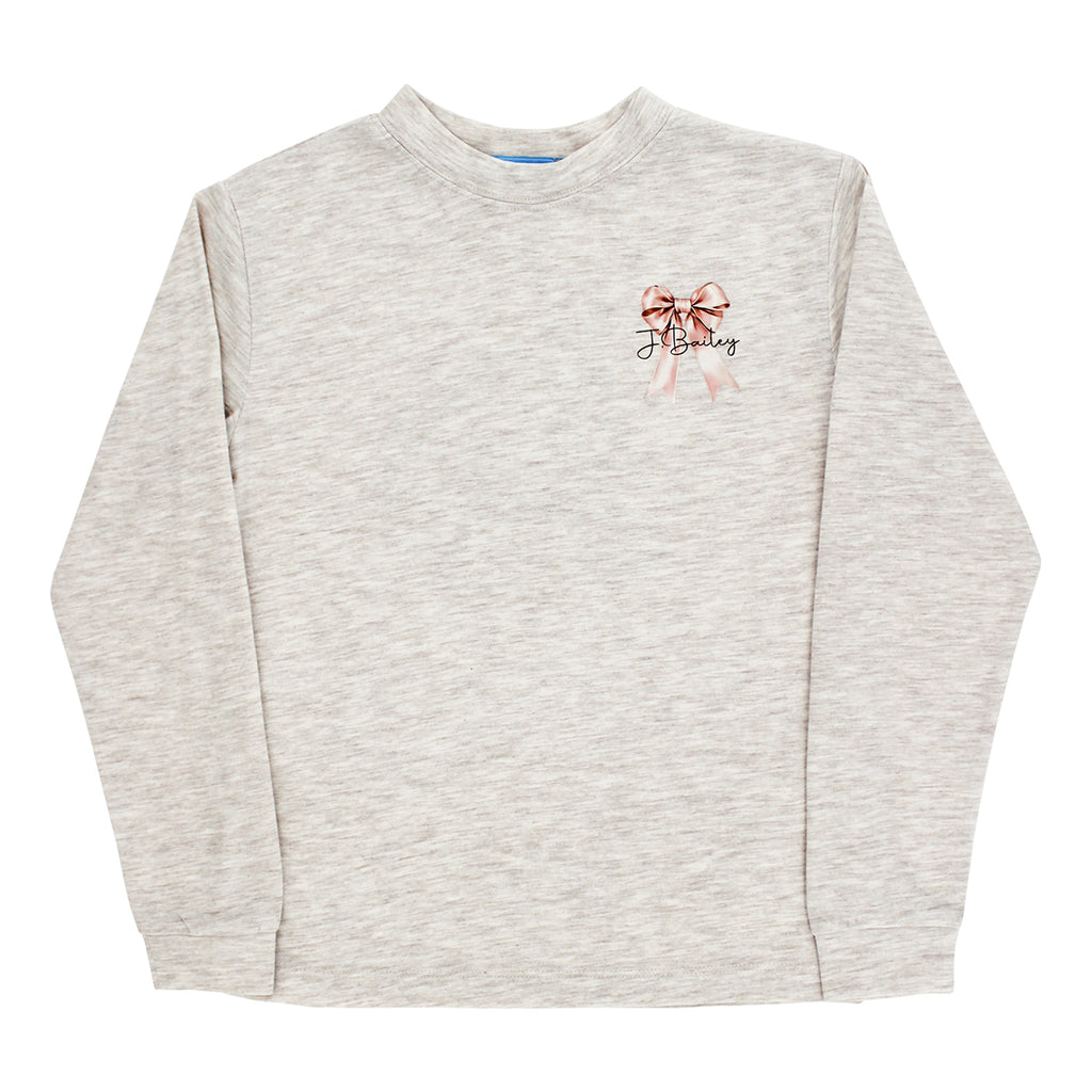 A girl's light heather beige long-sleeve crewneck sweatshirt with a pink bow and a J. Bailey logo on the front.