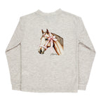 A girl's light heather beige long-sleeve t-shirt with a detailed graphic of a horse wearing a pink bow on its halter.