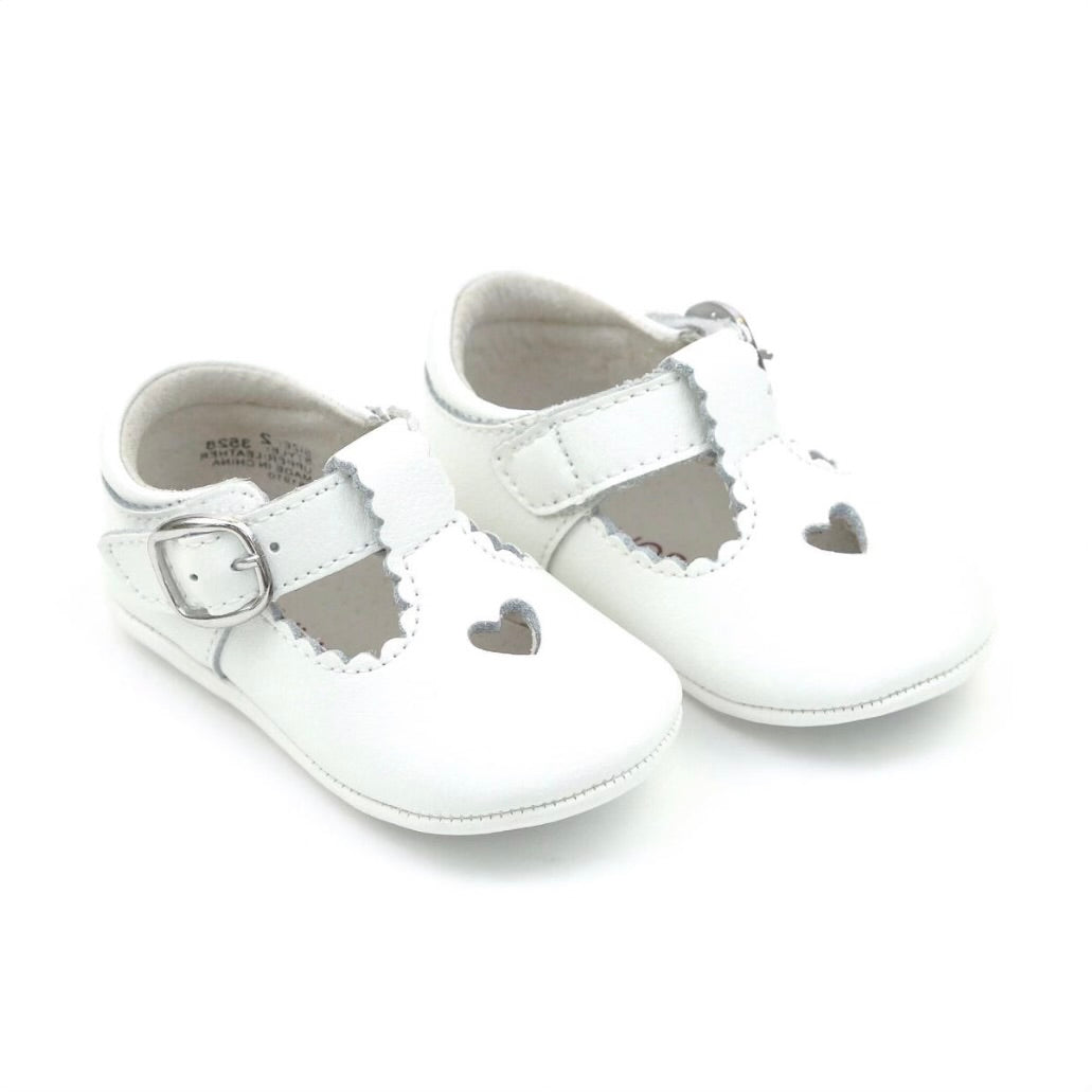 Pair of white baby girl shoes with a heart cutout and T-strap design.