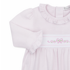 A close-up of a girl’s long-sleeve baby romper in pale pink and white stripes, featuring a ruffled collar and cuffs with pink bow and floral embroidery.