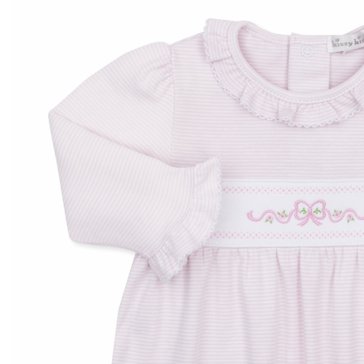 A close-up of a girl’s long-sleeve baby romper in pale pink and white stripes, featuring a ruffled collar and cuffs with pink bow and floral embroidery.