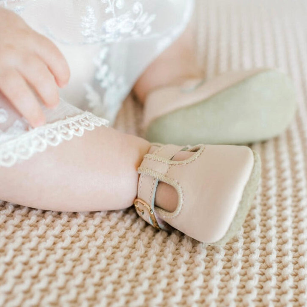 Baby girl’s feet with blush pink T-strap crime shoes
