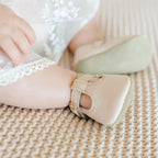 Baby girl’s feet with blush pink T-strap crime shoes