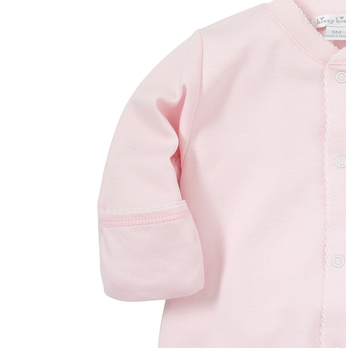Close-up of a baby gown in light pink, showing the sleeve cuff and white picot trim.