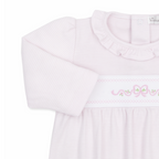 A close-up of a girl’s long-sleeve baby sack in pale pink and white stripes, featuring a ruffled collar and pink bow and floral embroidery.