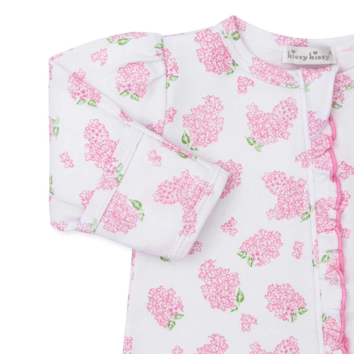 Closeup of a baby girl zip front footie with pink hydrangea floral pattern, ruffle trim, and Kissy Kissy brand label