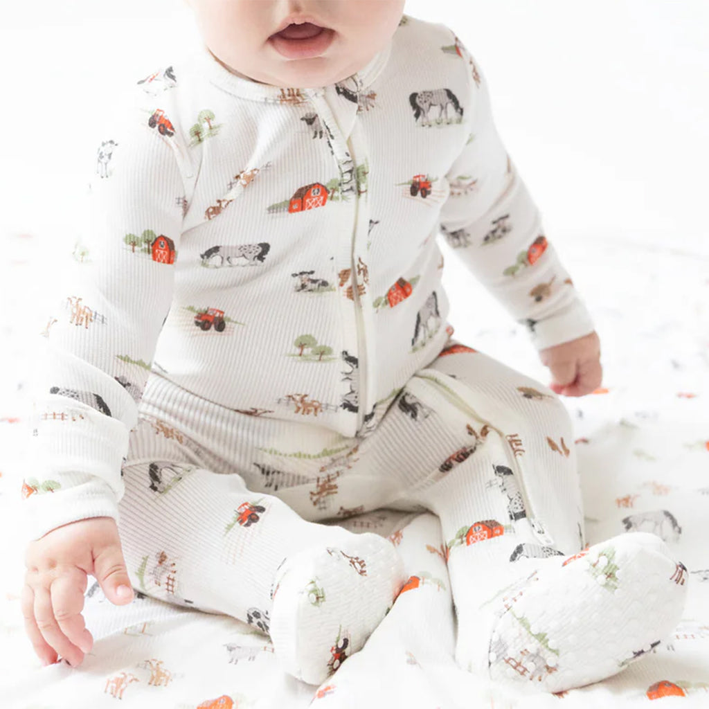 Baby boy wearing a cozy farm print footie with a zip front.