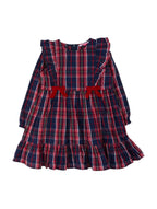A toddler girl's long-sleeve dress in a navy blue, red, and white plaid pattern, featuring ruffled shoulders, a red bow at the waist, and a ruffled hem, shown against a plain light gray background.