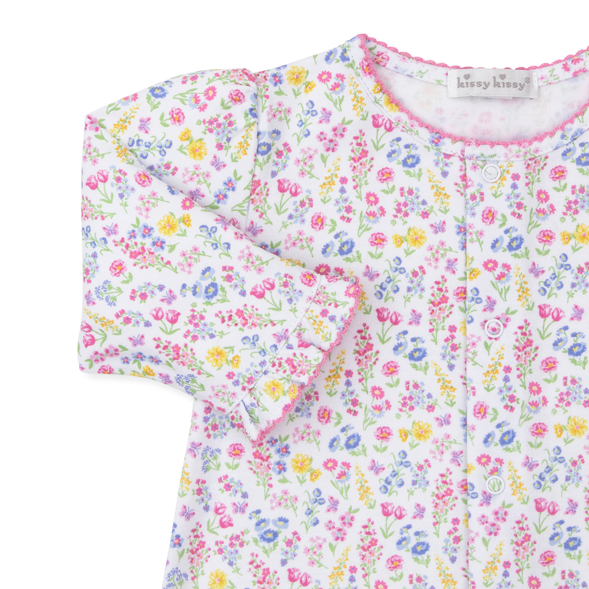Closeup of a baby girl converter gown with a bright floral pattern and Kissy Kissy brand label