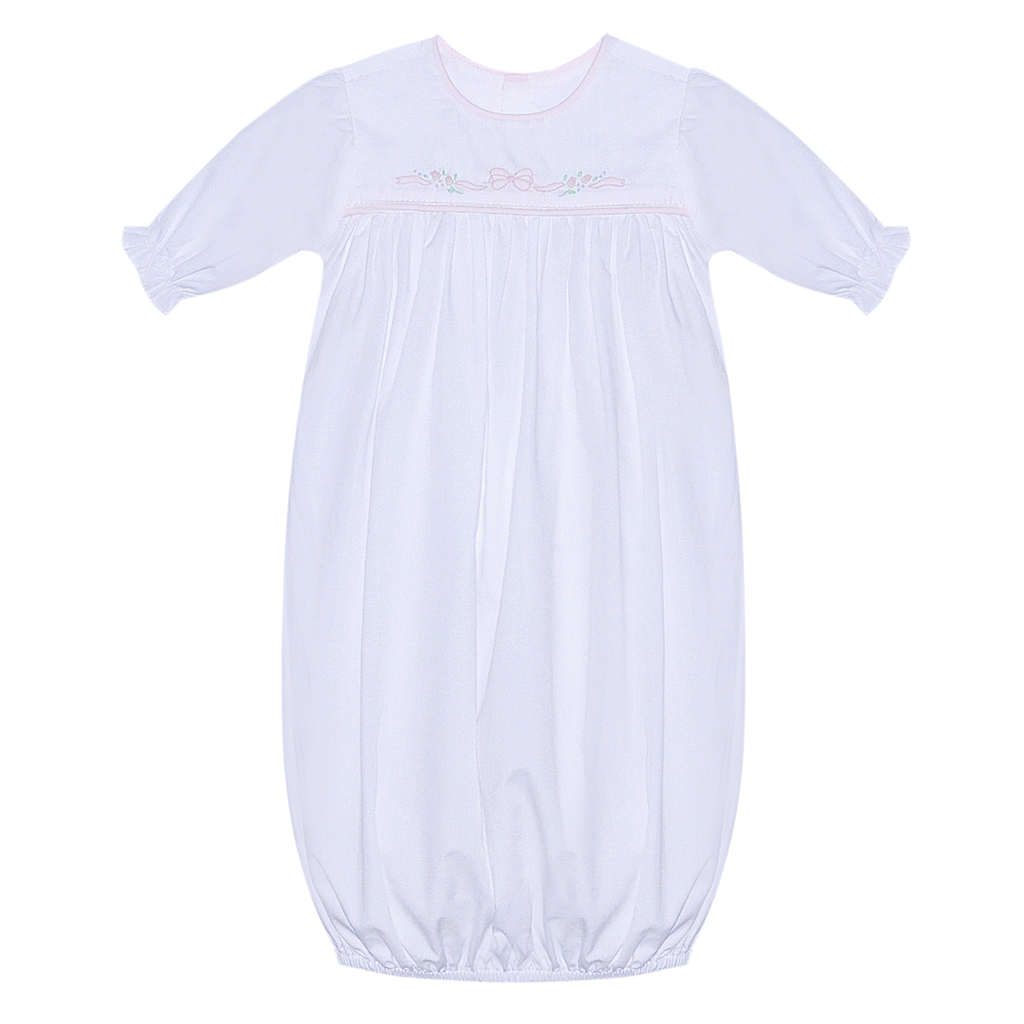 A white baby sleep sack with long sleeves, a round neckline, and delicate light pink bow and floral shadow embroidery across the chest.