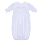 A white baby sleep sack with long sleeves, a round neckline, and delicate light pink bow and floral shadow embroidery across the chest.