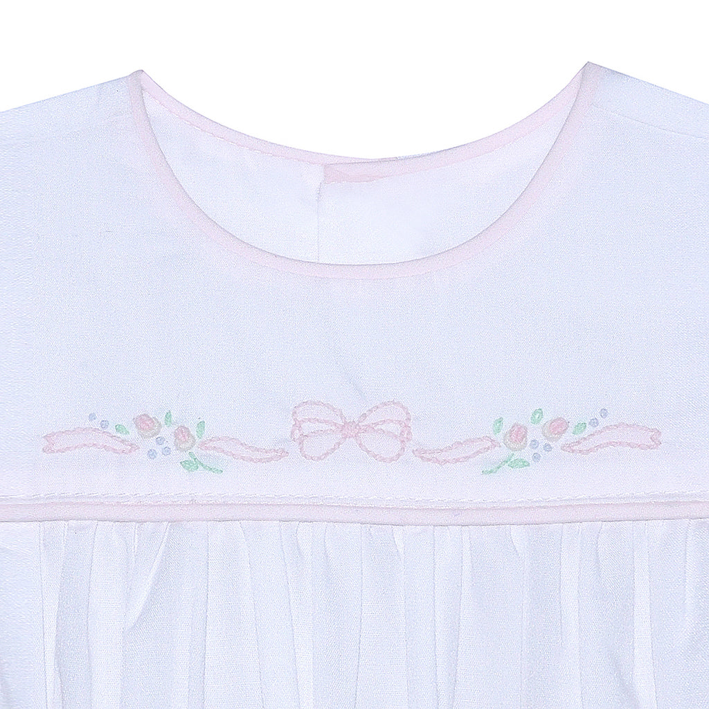 Close up of a white baby sleep sack with a round neckline and delicate light pink bow and floral shadow embroidery across the chest.