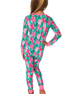 A woman shown from the back wearing a long-sleeve pajama set with a bright tropical floral print in green, pink, and white, with solid pink cuffs and collar.