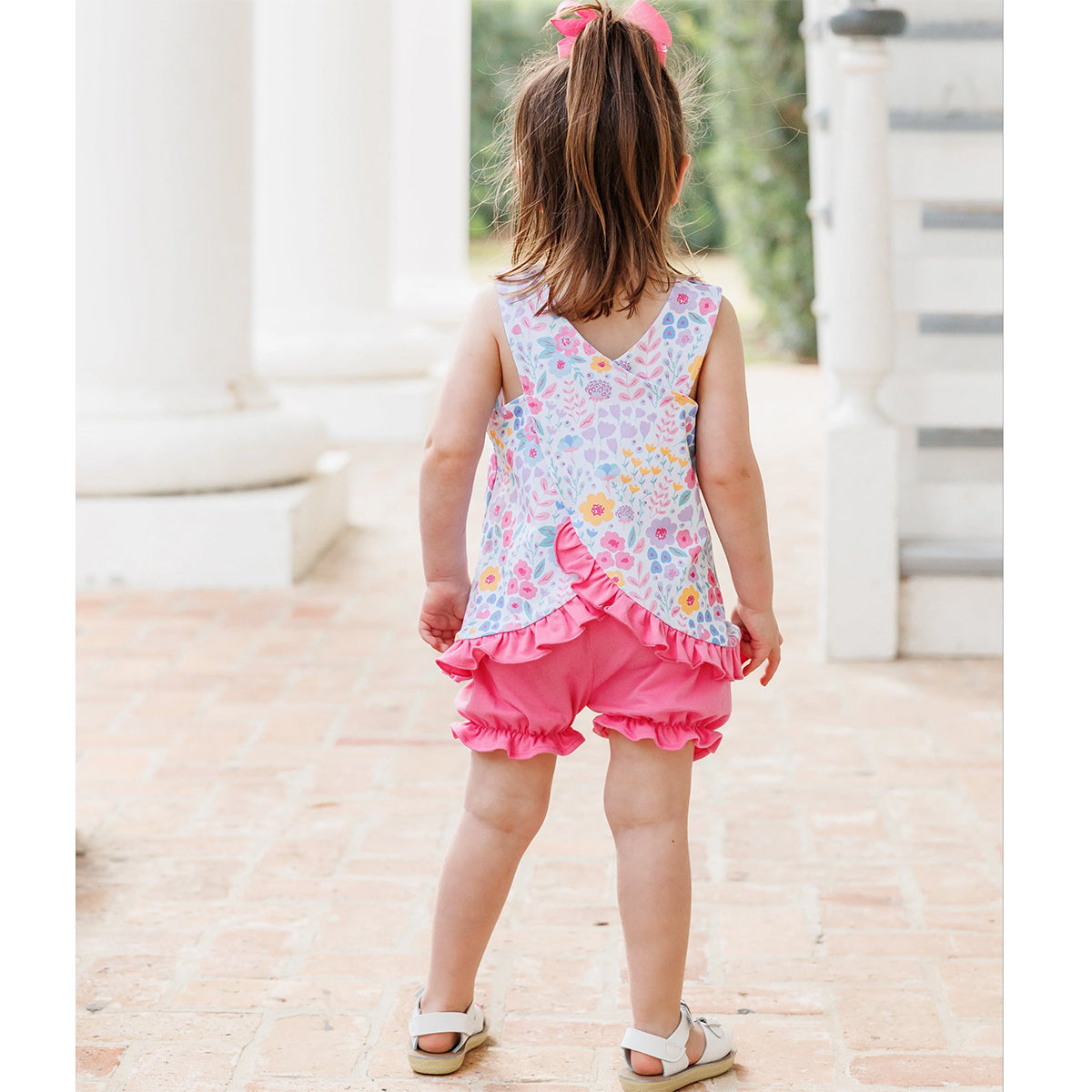Little girl wearing a floral swing back style sleeveless top and pink bloomers. 