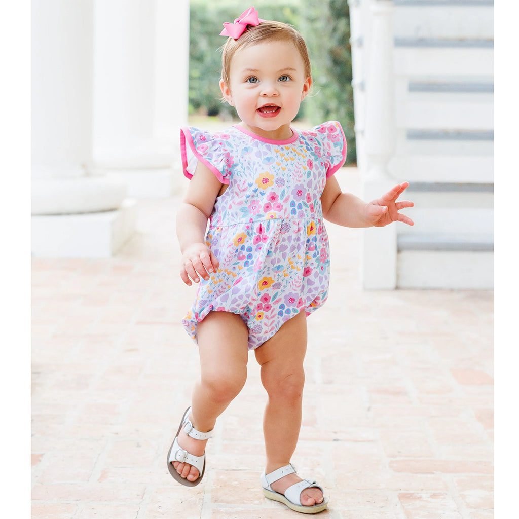 Baby girl in a summer floral bubble, pink hairbow and white sandals.