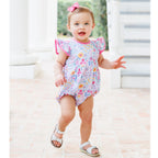 Baby girl in a summer floral bubble, pink hairbow and white sandals.