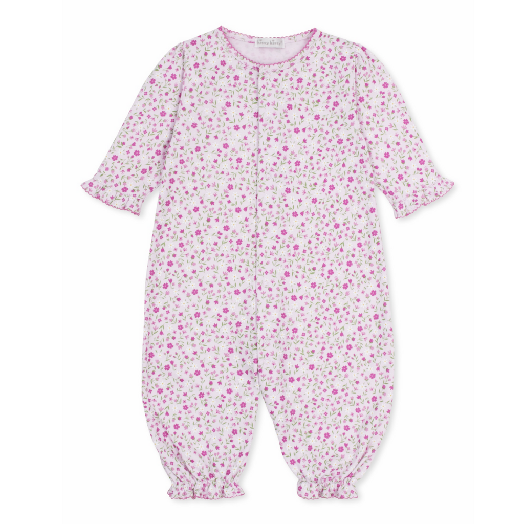 A baby girl pink converter gown playsuit with a floral print, hot pink trim, and ruffles at the wrists. 
