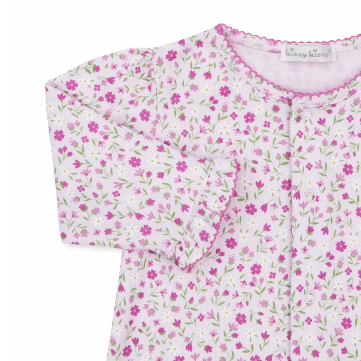 A baby girl pink converter gown closeup with a Kissy Kissy brand label, floral print, hot pink trim, and ruffles at the wrists.