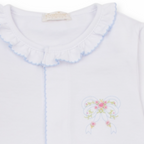A white long-sleeve baby girl converter gown closeup with ruffled collar and cuffs, light blue trim and a delicate embroidered bow with pink rosettes. 