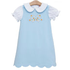 A light blue toddler girl dress outfit with a white Peter Pan collar short-sleeve knit shirt and a blue A-line jumper featuring an applique bow with embroidered pumpkins.