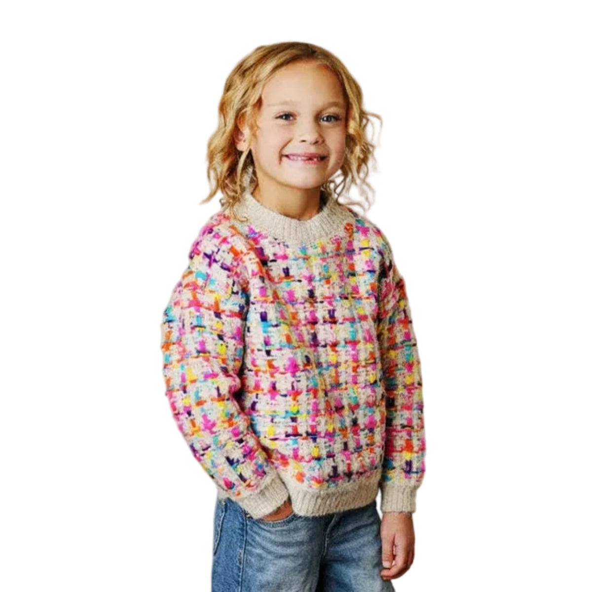 Child wearing a colorful sweater and blue jeans standing on a wooden floor.