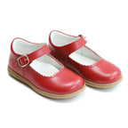 Pair of little girl’s red shoes with a buckle on a white background