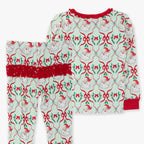 A two-piece children's pajama set featuring a long-sleeve top and matching pants with a festive Christmas print of Santa Claus, red bows, holly, and green leaves on a white background with red trim.