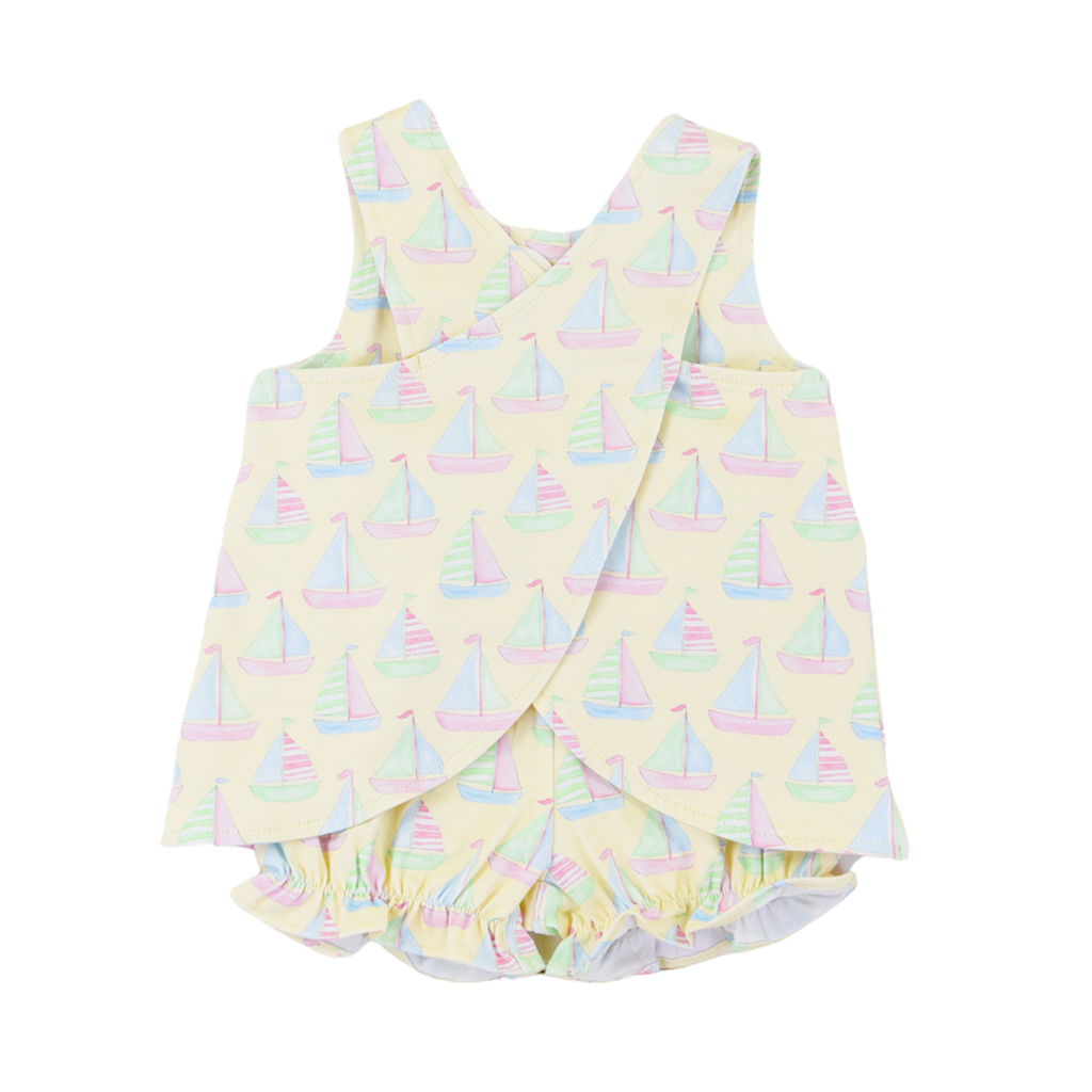 The criss cross back of a girls pale yellow summer bloomer set with a pastel sailboats print design.