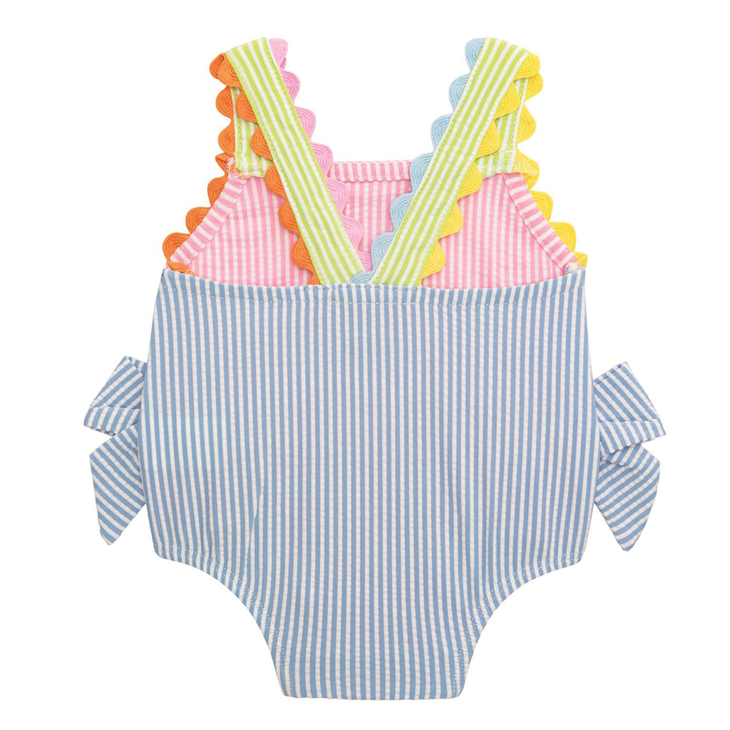 The back view of a pink striped seersucker girl's one-piece swimsuit with colorful ric-rac trim and blue bows on the hips.