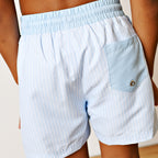 Back view of light blue striped boy swim trunks with a solid blue waistband and back pocket.