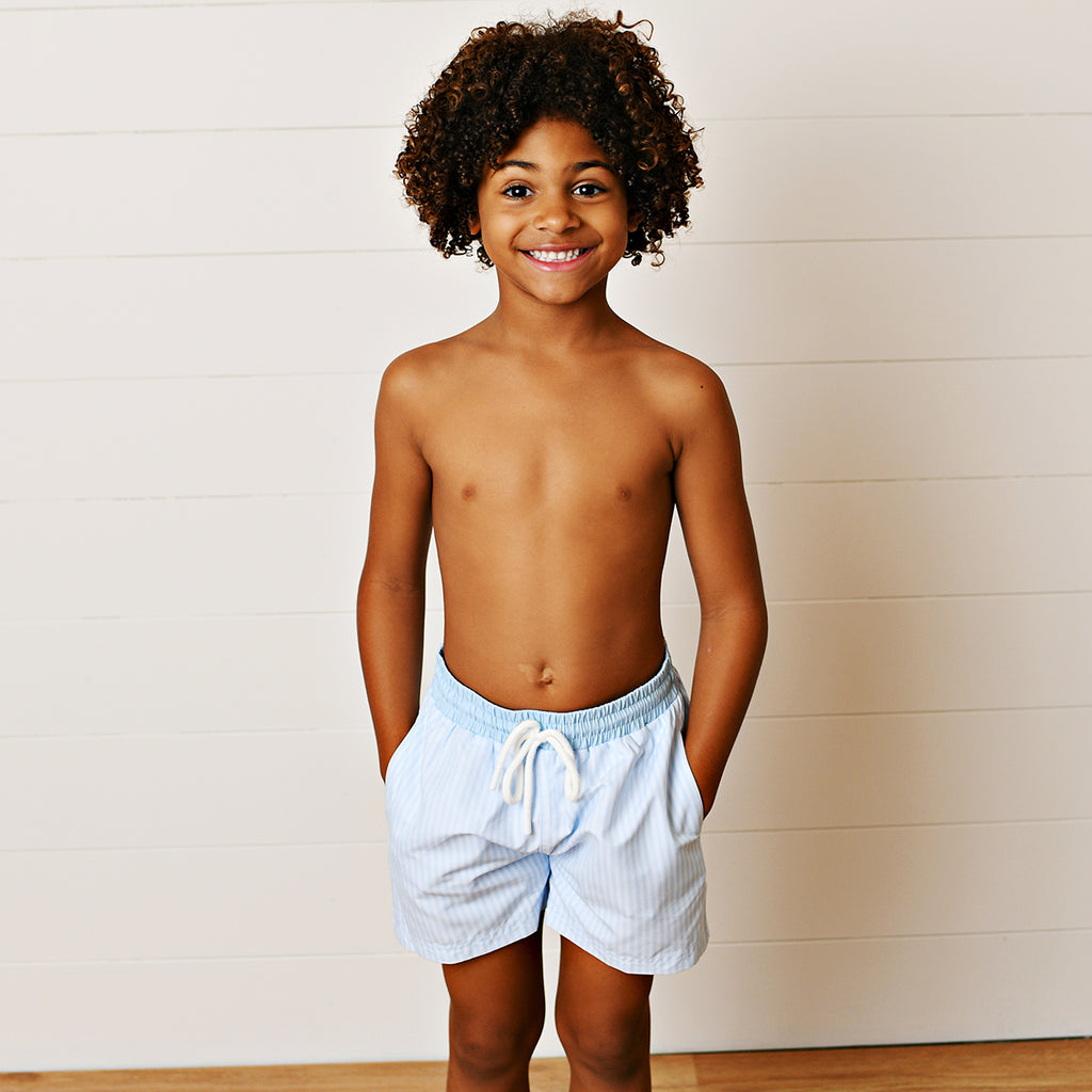 Boy wearing a light blue stripe swimsuit with a solid blue band and a drawstring.