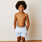Boy wearing a light blue stripe swimsuit with a solid blue band and a drawstring.